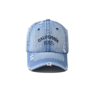 Close-up of distressed denim baseball cap with California Surf embroidery and worn texture