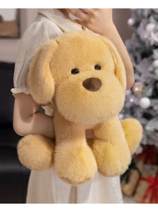 Dettaglio di un peluche di Golden Retriever tenuto davanti a uno sfondo natalizio