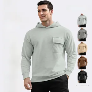 Detail view of the chest flap pocket and stitching on a light green hooded sweatshirt