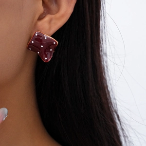 Detail of red square resin stud earring with white polka dots on model ear