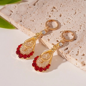 Detailed macro view of teardrop mesh earrings with red zircon in gold-plated finish