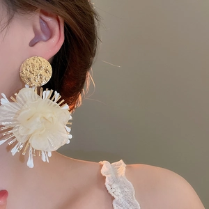 Detailed view of elegant white chiffon flower earrings with golden hammered metal texture