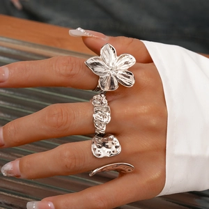 Macro shot of silver crinkled flower ring and textured geometric bands set on fingers