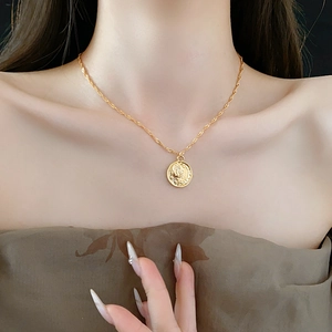 Close-up of a gold retro coin pendant necklace with a twisted rope chain on a model's neck