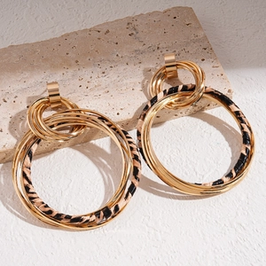 Makroansicht mehrlagiger goldener Metallohrringe mit Vintage-Leder in Leoparden-Optik