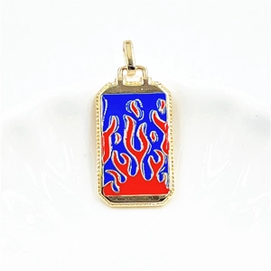 Macro detail of a rectangular gold pendant featuring red and blue enamel fire design