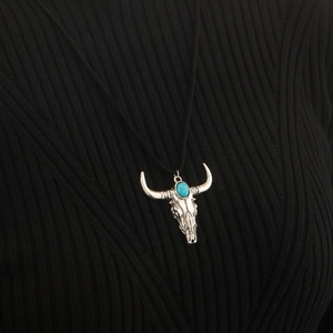Detail of western bull skull necklace with turquoise inlay on black knitwear
