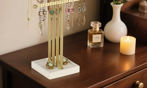 Detail view of gold 4-tier jewelry stand with earring holes and white tray base