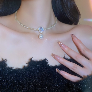 Detail of gold-plated choker featuring a teardrop zircon and pearl pendant on a model