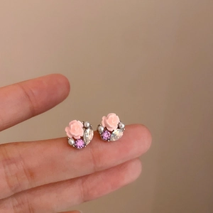Dettaglio di orecchini a rosa rosa con cristalli viola e piccole perle bianche