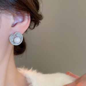 Close-up of pearl stud earring with zircon accents worn by a model in soft lighting