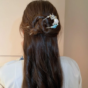 Detailaufnahme einer U-förmigen Meeres-Haarnadel mit Seestern und Perlen in einer Frisur