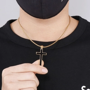 Close-up of gold twist chain necklace with black and gold cross pendant on male model