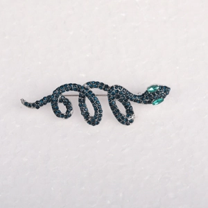 Detailansicht einer Schlangenbrosche mit dunkelblauen und grünen Rhinestones