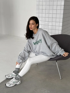 Close-up of grey oversized sweatshirt with legacy letter print and ribbed crew neck details