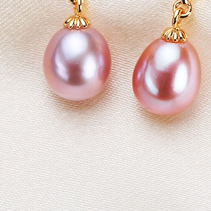 Pink teardrop freshwater pearl earrings with gold ginkgo leaf hooks on silk background