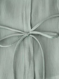 Detail of sage green sheer blouse fabric with an elegant matching pussy bow tie design