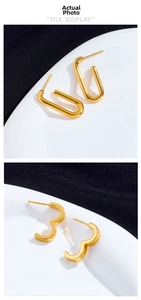 Detail of gold titanium steel earrings with U-shaped and wavy geometric metal designs