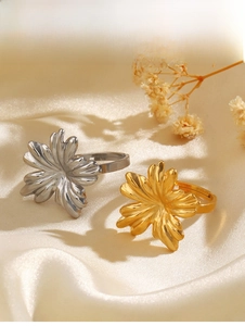 Detail of adjustable flower rings in gold and silver finish on elegant silk fabric