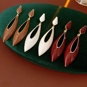 Macro shot of vintage enamel drop earrings in brown white and red on green velvet