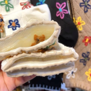 Close-up of ribbed cuffs and colorful floral embroidery on retro knit cotton socks