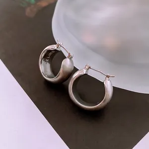 Vue macro détaillée de boucles d'oreilles créoles en argent brossé avec gravure de marque