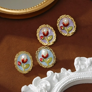 Detail of baroque pearl earrings with enamel floral patterns in vintage gold frames