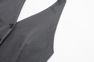 Détail du gilet tissé gris avec coutures précises et bouton noir sur le devant