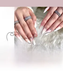 Macro shot of pink gradient press-on nails with heart patterns and rhinestone accents
