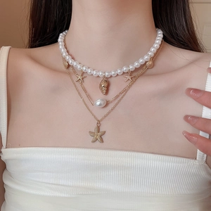 Close-up of layered necklace with baroque pearl, golden starfish and shell charms