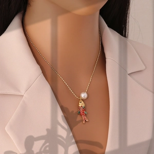 Détail d'un collier avec pendentif poisson koi, perles et chaîne dorée sur un mannequin