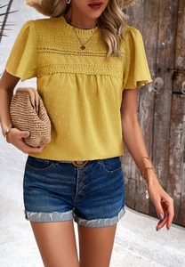 Detail of yellow round neck top featuring pleated lace trim and polka dot texture fabric