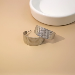 Minimalist silver C-shape earrings with textured metal surface and wide hoop geometry