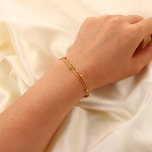 Double-layered 18K gold bead chain stainless steel bracelet worn on silk fabric