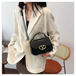 Fashionable black patchwork handbag for women styled with a cream blazer and gold hardware