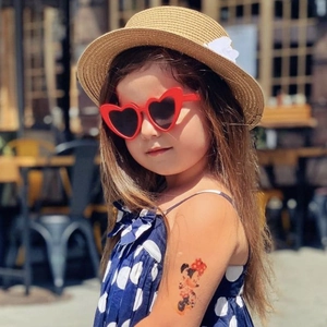 Fillette portant des lunettes de soleil coeur rouges et un chapeau de paille au soleil