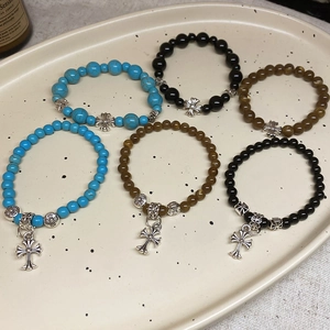 Détail de bracelets en perles de pierre avec croix en argent vintage et perles à fleurs