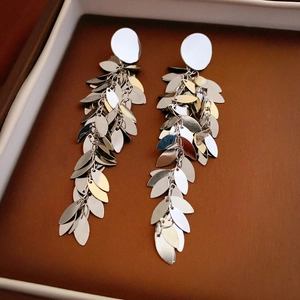 Macro detail of long tassel leaf earrings with metallic silver and gold sequins in a box
