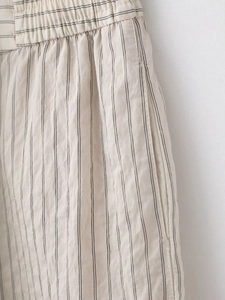 Detail of elastic waistband and side pocket on beige striped cotton-linen set