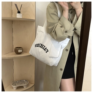 Close-up of white canvas tote bag with FASHION logo and detachable mini zipper pouch