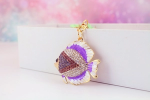 Detailed close-up of a golden tropical fish keychain with purple rhinestones and enamel