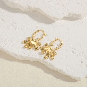 Close-up of gold irregular floral metal earrings with a textured surface and glossy finish