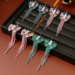 Dettaglio di orecchini vintage a farfalla con nappe nei colori blu, rosa e verde zircone
