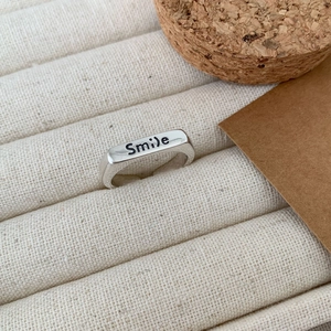 Minimalist 925 sterling silver Smile ring displayed on a beige jewelry display tray