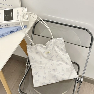 Detail of white canvas tote bag featuring light blue cat floral prints on a folding chair
