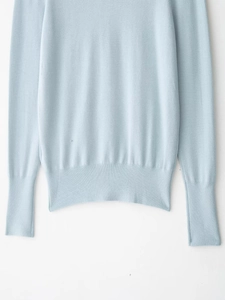 Close-up of light blue knit sweater showing detailed texture on hem and ribbed cuffs