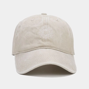Close-up of beige washed cotton baseball cap featuring detailed white sun embroidery