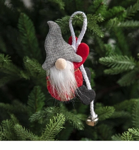 Close-up of fabric gnome ornament with golden bell hanging on a Christmas tree branch