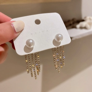 Detail of elegant pearl stud earrings with long crystal tassel fringe in gold finish