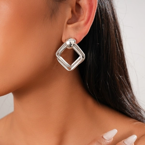 Gros plan de boucles d'oreilles argentées géométriques portées par un mannequin